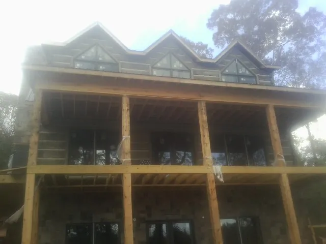 Dormers and porch framing on a large log home under construction — Roof Coating work by our crew in Galesburg