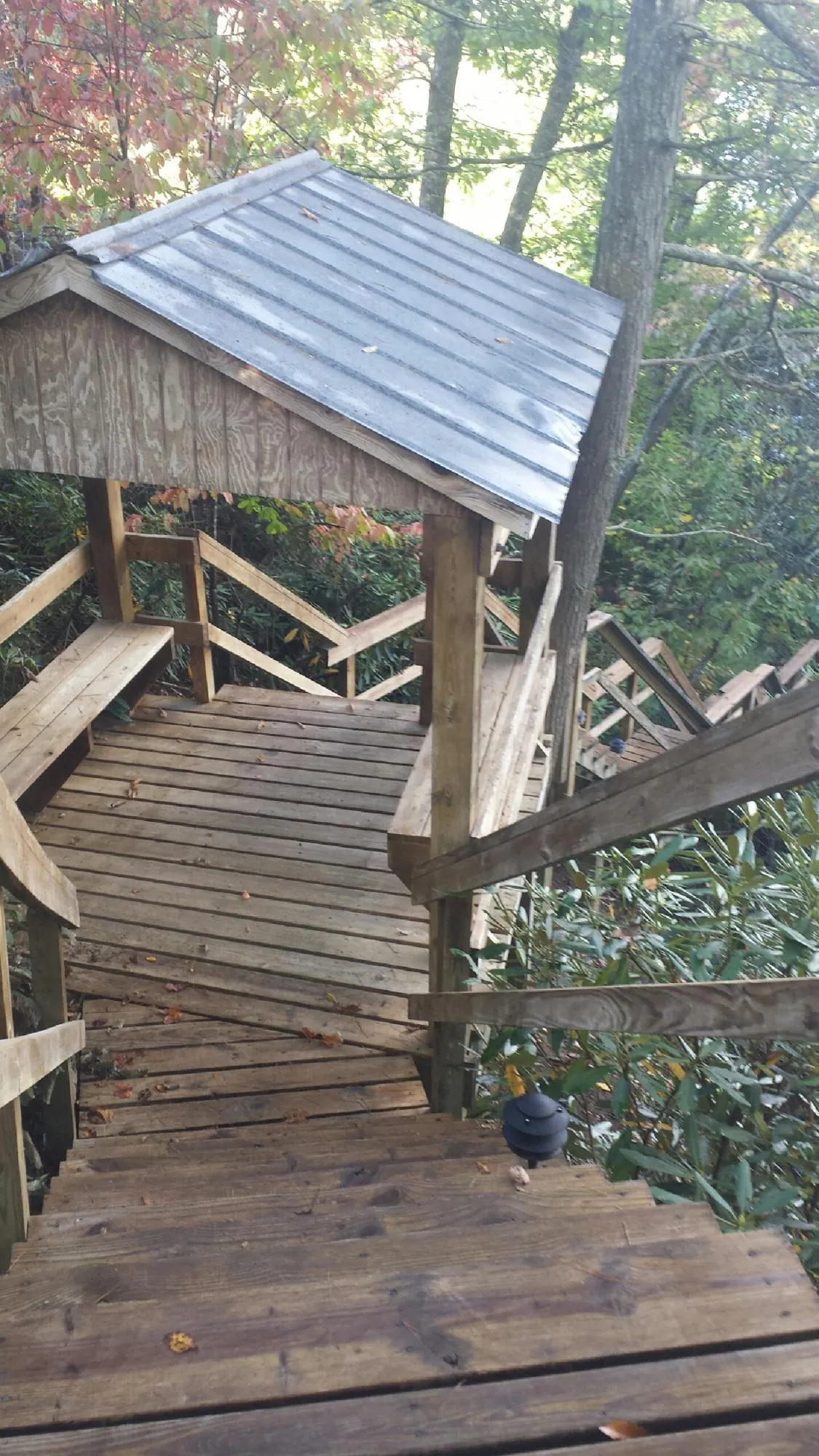 Metal roofed shelter over wooden steps on a wooded walkway — Skylight Repair & Installation work by our crew in Galesburg